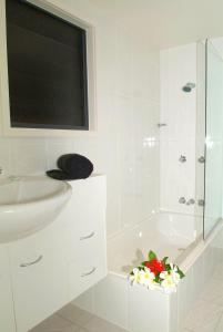 a white bathroom with a sink and a bath tub at Canopy Chalet 4 in Nelly Bay