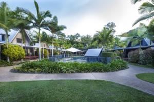 a courtyard with palm trees and a house at Canopy Chalet 4 in Nelly Bay