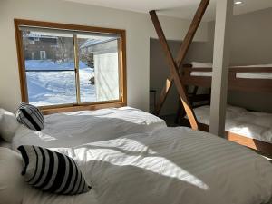 a bedroom with two white beds and a window at Hakuba Sunrise Apartments in Hakuba
