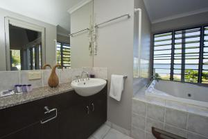 a bathroom with a sink and a tub and a mirror at Magnetic Docks Townhouse 9 in Nelly Bay +13 photos