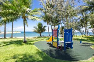 two colorful playground equipment on the beach with palm trees at Magnetic Docks Townhouse 9 in Nelly Bay