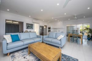 a living room with two blue couches and a table at Sandy Decks in Nelly Bay