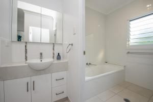 a white bathroom with a sink and a bath tub at Sandy Decks in Nelly Bay +17 photos