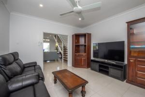 a living room with a couch and a flat screen tv at Sandy Decks in Nelly Bay