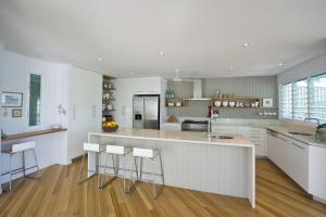a kitchen with white cabinets and a counter with bar stools at The Boathouse in Nelly Bay