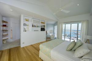 a white bedroom with a large bed and a window at The Boathouse in Nelly Bay
