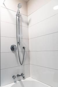 a shower in a white tiled bathroom with a sink at Turner Heights Townhouses in Queenstown