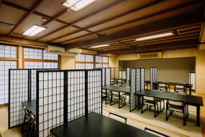 een restaurant met zwarte tafels en stoelen en ramen bij Hisaeya Ryokan in Fujioka