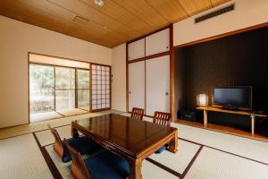 sala de estar con mesa y TV en Hisaeya Ryokan, en Fujioka