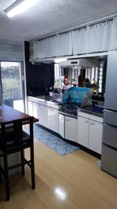 a kitchen with white cabinets and a wooden table and a tableablish at 宮古島ゲストハウス　マウイ in Arazato