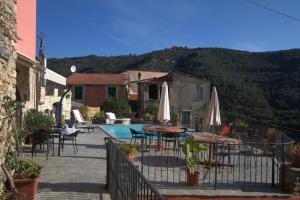 un patio con mesas y sombrillas junto a una piscina en Appartamenti Chiarina, en Dolcedo