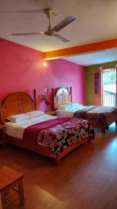 twee bedden in een kamer met roze muren bij Posada El Volador in Cuetzalán del Progreso