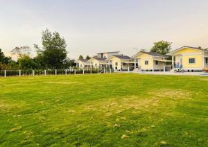 a large grass field with houses in the background at PPN Garden Resort in Suwannaphum