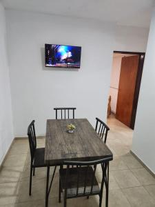 mesa de comedor con sillas y TV en la pared en Departamento Capital en La Rioja