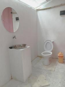 uma casa de banho branca com um WC e um espelho. em Kubu Container em Uluwatu