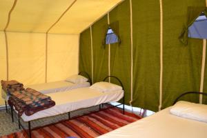 a room with three beds in a green tent at Mhamid Sahara Camp - Mhamid El Ghizlane in Mhamid