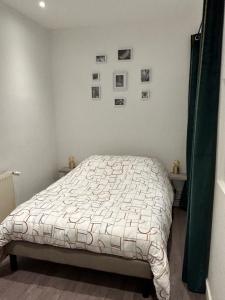 - une chambre avec un lit et des photos sur le mur dans l'établissement Le voltaire 1 chez Adrien, à Saint-Quentin