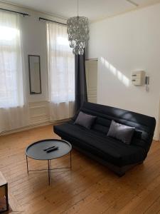 um sofá preto numa sala de estar com uma mesa em Le Voltaire 4 chez Adrien Hyper centre em Saint-Quentin