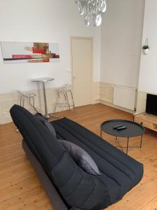 um sofá preto numa sala de estar com duas mesas em Le Voltaire 4 chez Adrien Hyper centre em Saint-Quentin