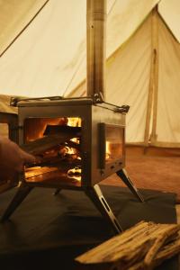 a stove with a fire in a tent at Numie - Freycinet Peninsula - Glamping in Coles Bay