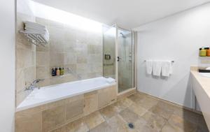 a white bathroom with a tub and a shower at Holiday Inn Sydney Potts Point in Sydney