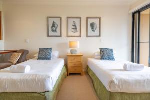 a bedroom with two beds and a table with a lamp at Cavvanbah Beach Villa in Byron Bay