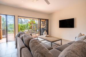 a living room with a couch and a tv at Cavvanbah Beach Villa in Byron Bay