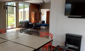 Una sala de estar con una mesa y sillas y un televisor. en El Chasqui Guest House, en Chasqui