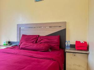 SampitにあるGreenville Hotel Mitra RedDoorzの赤いシーツと木製のヘッドボード付きのベッド