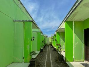 a corridor of green buildings with plants in pots at Greenville Hotel Mitra RedDoorz in Sampit