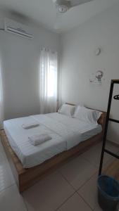 Gopeng Serumah Holiday House في Gopeng: سرير بشرشف ووسائد بيضاء في الغرفة