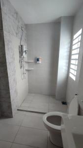 Gopeng Serumah Holiday House في Gopeng: حمام أبيض مع دش ومرحاض