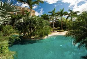 une grande piscine bordée de palmiers et un bâtiment dans l'établissement Matapalo 101- 3 Bedroom Poolside Luxury Condo at the Diria Resort, à Tamarindo