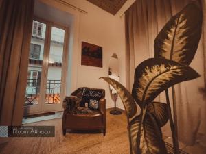 ein Wohnzimmer mit einem Stuhl und einer Pflanze in der Unterkunft CITRUS LUXURY APARTMENT - holiday apartment with up to 3 bedrooms in palermo center in Palermo