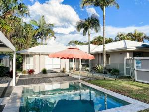 a house with a swimming pool with an umbrella at Perfect Noosa Pad with Pool in Noosaville