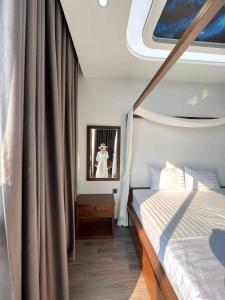1 dormitorio en un yate con cama y espejo en Sun Villa- Flamingo Venus Đại Lải, en Vĩnh Phúc