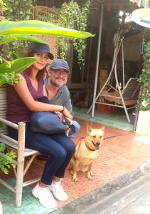 a man and a woman sitting on a bench with a dog at Srikrung Guesthouse in Phra Nakhon Si Ayutthaya