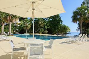 uma mesa e cadeiras com um guarda-sol ao lado de uma piscina em Stunning Ocean View em Negril