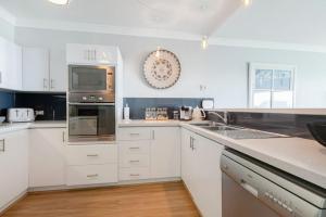 una cocina con armarios blancos y electrodomésticos de acero inoxidable en Suite 305 Sandcastles 3 Bedroom Deluxe Apartment en Perth