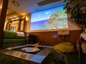 uma sala de estar com uma mesa e um grande ecrã em We Home Villa ～城ケ崎温泉～ em Futo