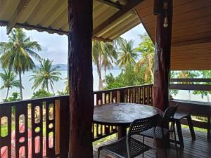 a balcony with a table and chairs and the ocean at Three Monkeys Bungalows Koh Yao Noi in Ko Yao Noi