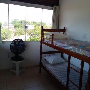 1 dormitorio con litera, ventilador y ventana en OTIMO APARTAMENTO EM JACARAIPE ES ! en Serra