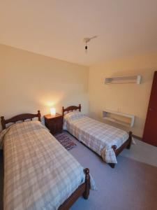 1 dormitorio con 2 camas y mesa con lámpara en Los Malvones en Viedma