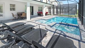 uma piscina com cadeiras e uma casa em Luxury 9BR Villa @ Storey Lake Resort Near Disney em Kissimmee