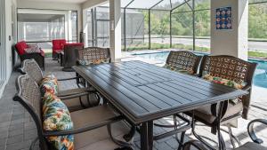 un patio con mesa, sillas y piscina en Luxury 9BR Villa @ Storey Lake Resort Near Disney, en Kissimmee