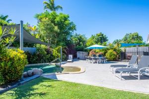 un patio trasero con piscina, sillas y sombrilla en Island View Apt 1 en Arcadia