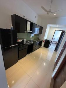 可倫坡的住宿－Fully Furnished Apartment，厨房配有黑色家电和白色瓷砖地板。