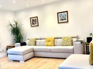 a living room with a white couch with yellow pillows at Stunning 1 bedroom + double sofa bed & jacuzzi near Train station in Southampton