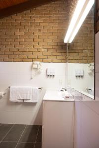 a bathroom with a white sink and a brick wall at Goldfields Motel in Stawell