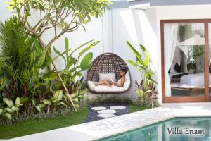 a woman sitting in a swinging chair next to a swimming pool at Villa Mia Seminyak - Boutique Villas in Seminyak